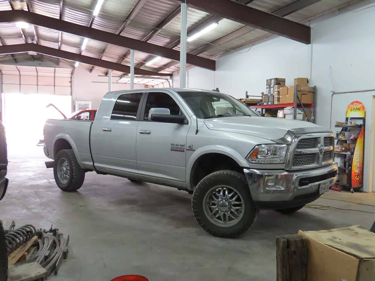White Ram truck with Cummins badge in auto repair shop.